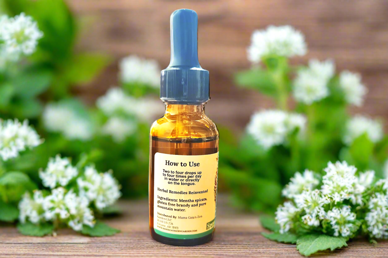 a bottle of Spearmint Flower Essence is displayed on a wooden table outdoor surrounded by spearmint flowers.